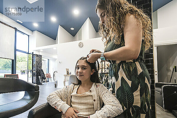 Friseur kämmt Mädchen im Salon die Haare