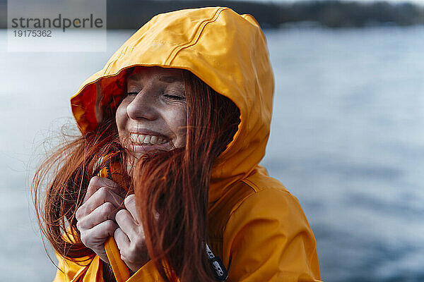 Lächelnde rothaarige Frau in gelber Jacke