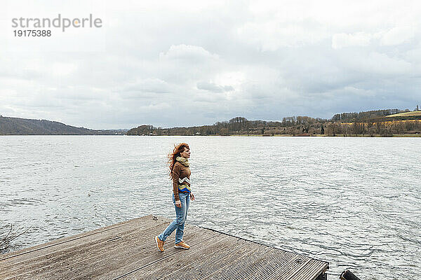 Woman spending leisure time on pier by lake
