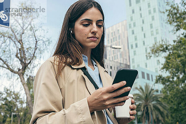 Junge Frau benutzt Smartphone in der Stadt