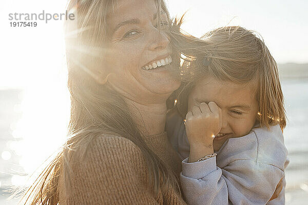 Cheerful woman with daughter at beach