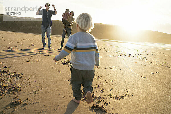 Fröhliche Familie  die zusammen am Strand spielt
