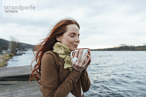 Frau trinkt Tee am See