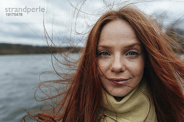 Redhead woman with long hair by lake