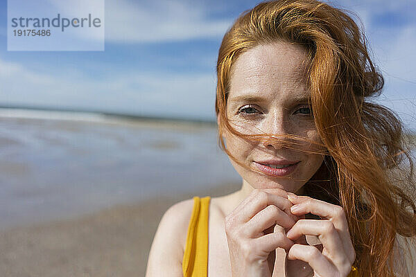 Frau mit Wind im Haar am Strand an einem sonnigen Tag