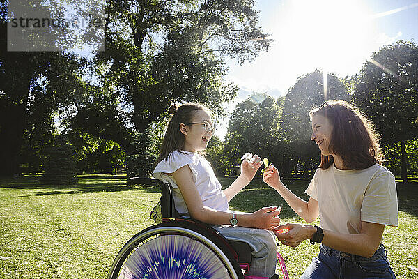 Glückliche Tochter im Rollstuhl und Mutter genießen den Park