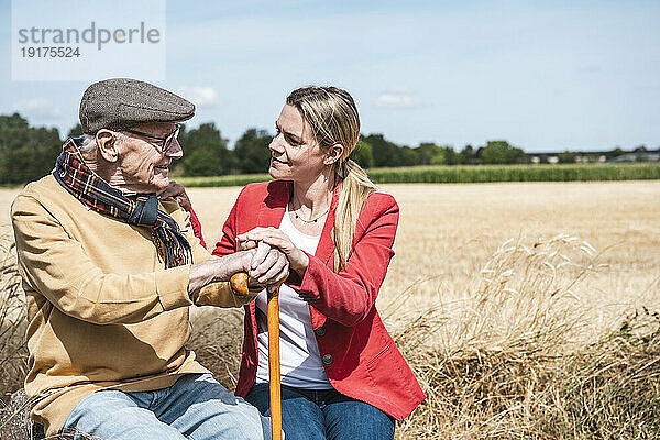 Frau spricht an sonnigem Tag mit älterem Mann auf dem Feld