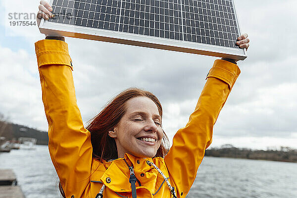 Smiling woman with eyes closed holding solar panel