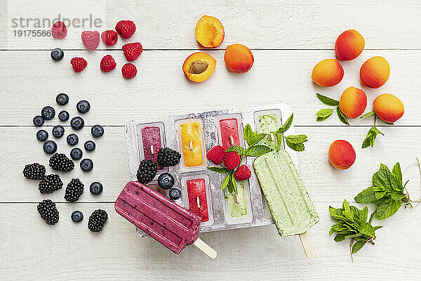 Raw berry fruits and homemade popsicles on wooden surface