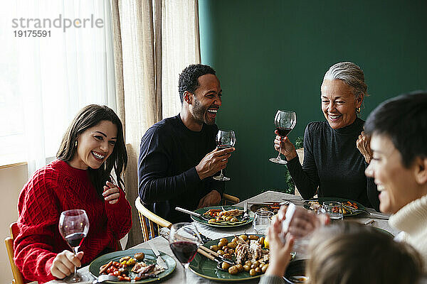 Glückliche Familie  die Rotwein trinkt und an Weihnachten eine Dinnerparty genießt