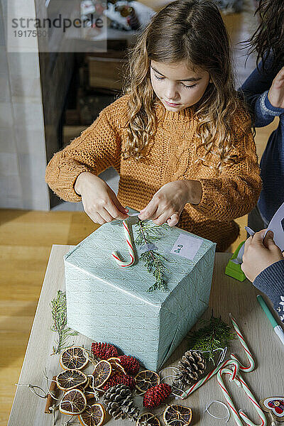 Girl decorating gift box with candy cane at home