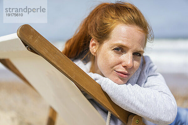 Redhead woman on deck chair at beach holiday