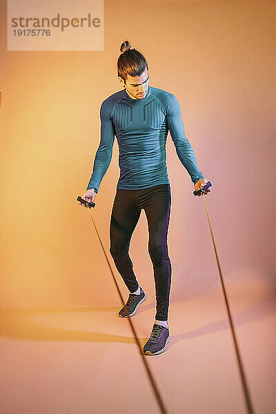 Man exercising with resistance band in front of backdrop