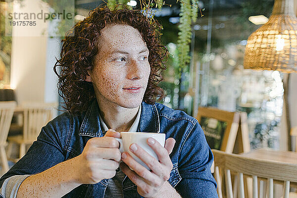 Lächelnder Mann hält Kaffeetasse im Café