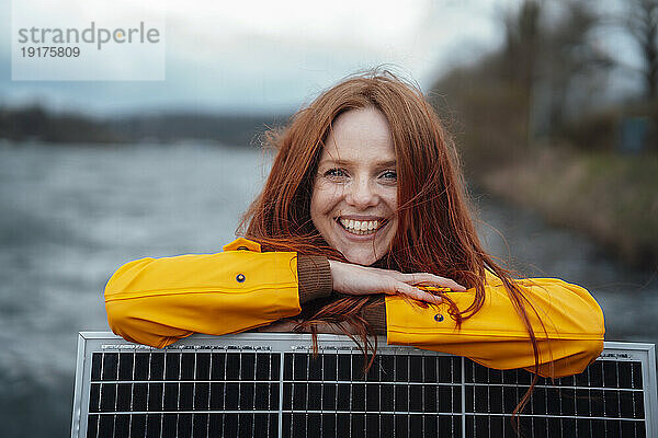 Happy redhead woman leaning on solar panel