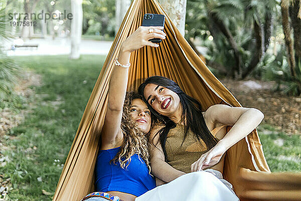 Lesbisches Paar macht Selfie mit Smartphone in Hängematte