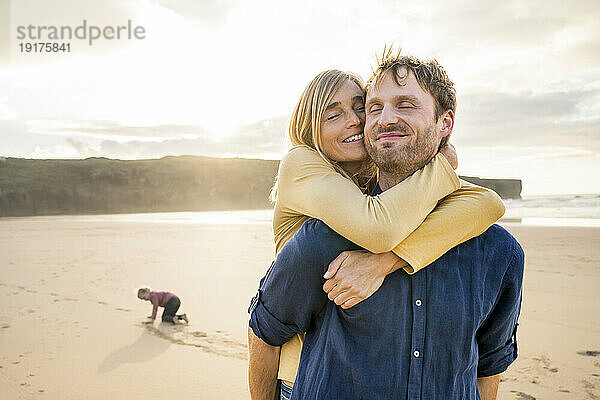 Happy woman hugging man at beach