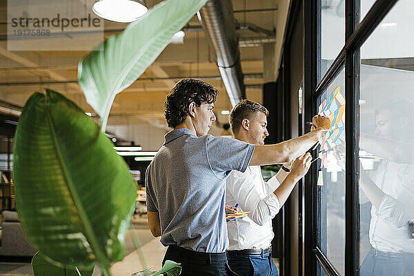 Geschäftsleute arbeiten in der Nähe einer Glaswand im Büro zusammen