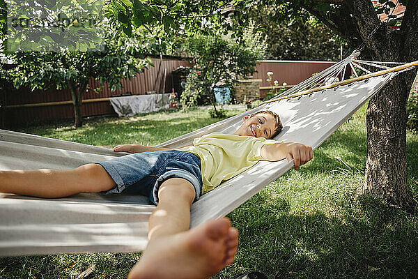 Happy boy relaxing on hammock in back yard