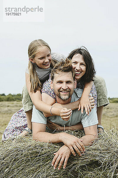 Glückliche Familie auf Heu im Feld unter Himmel