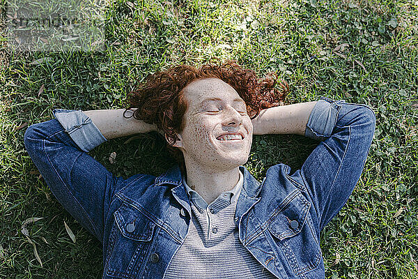 Lächelnder junger Mann  der sich im Gras entspannt