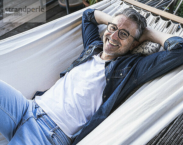 Happy mature man relaxing in hammock at home