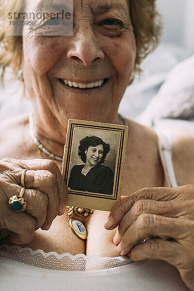 Senior woman holding old picture at home