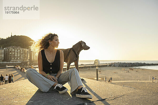 Frau verbringt ihre Freizeit mit Hund  der auf der Promenade sitzt