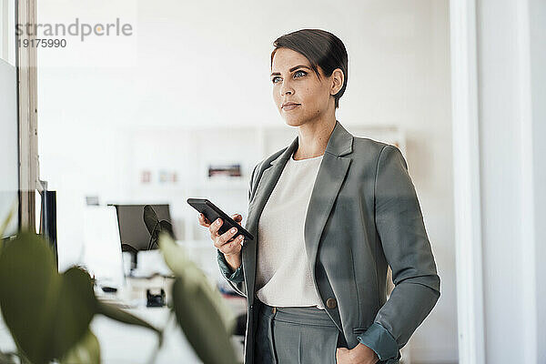 Selbstbewusste Geschäftsfrau mit Smartphone im Büro