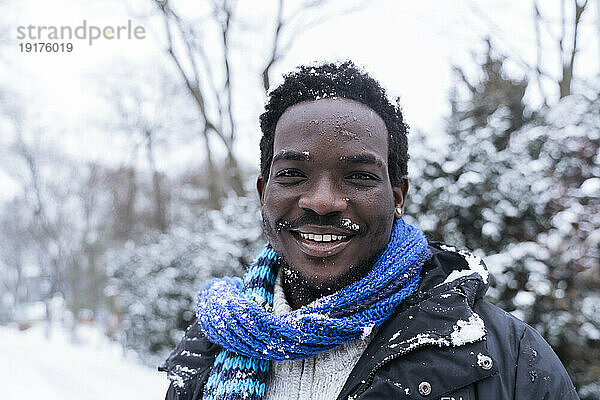 Glücklicher Mann mit blauem Schal im Winter