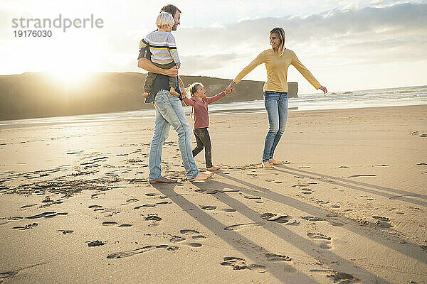 Smiling mother and father with children at beach on sunny day