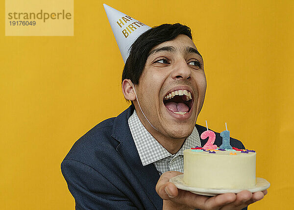 Fröhlicher Mann hält Kuchen zum 21. Geburtstag im Studio
