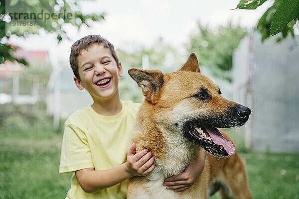 Glücklicher Junge mit Hund im Hinterhof
