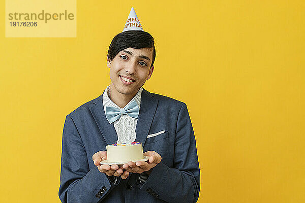 Lächelnder Mann hält Kuchen zum 18. Geburtstag im Studio