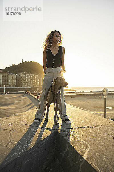 Junge Frau steht mit Hund auf der Promenade