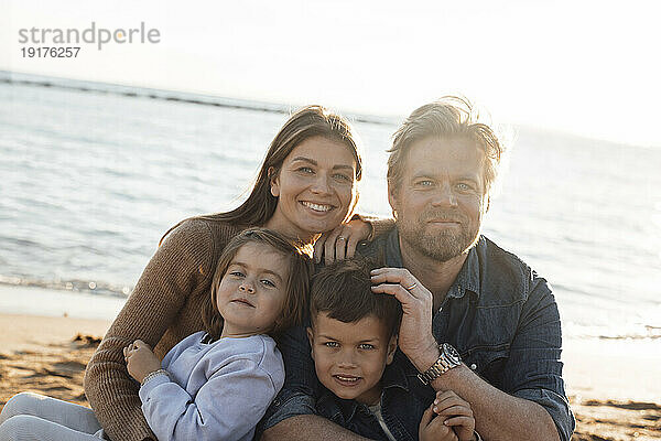 Lächelnde Mutter und Vater mit Kindern vor dem Meer