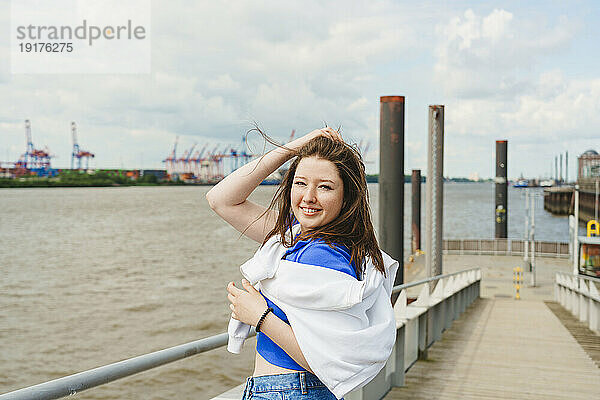 Teenager with hand in hair standing at harbor by Elbe river