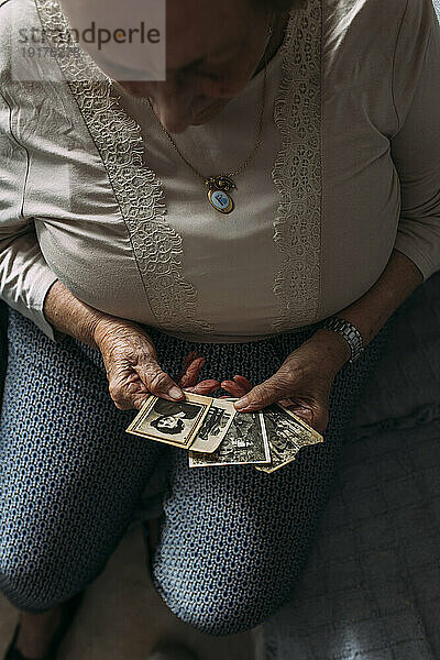 Ältere Frau betrachtet vergangene Fotos zu Hause