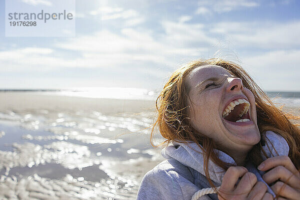 Frau lacht im Urlaub am Strand