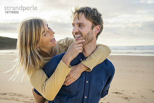 Fröhliche Frau genießt es mit Mann am Strand