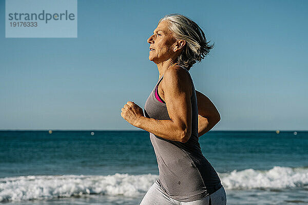 Reife Frau joggt am Strand am Meer