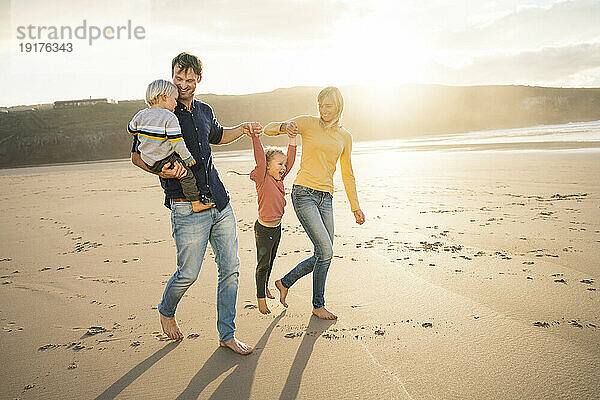 Fröhlicher Vater und Mutter genießen mit Kindern am Strand