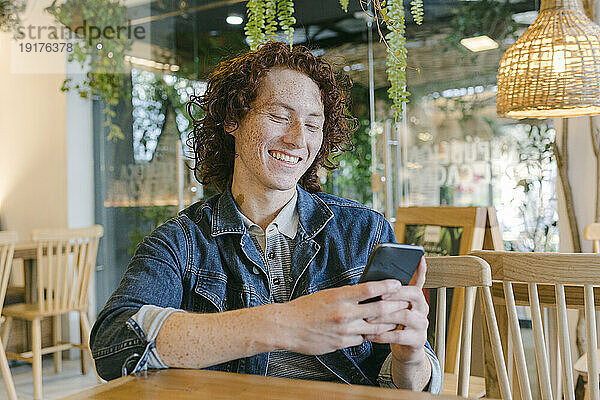 Glücklicher Mann benutzt Smartphone im Café