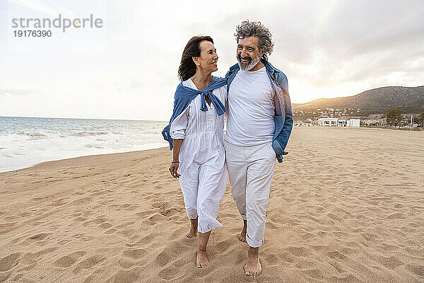 Glückliches älteres Paar  das am Strand auf Sand spaziert