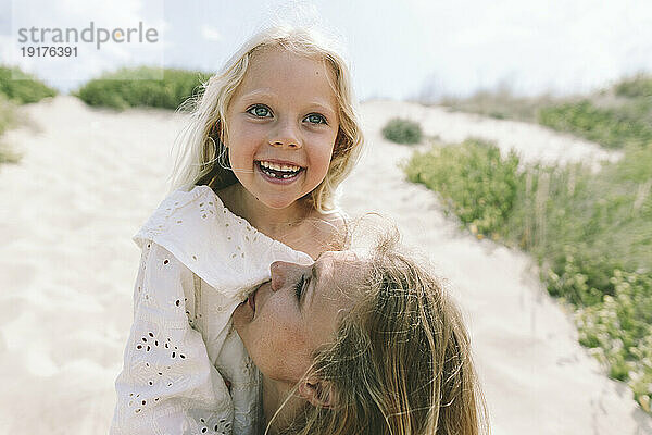 Liebevolle Mutter mit lächelnder Tochter am Strand