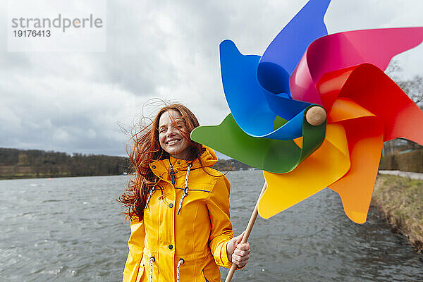 Lächelnde Frau mit Windradspielzeug vor dem See