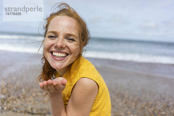 Fröhliche Frau gestikuliert im Sommerurlaub am Strand