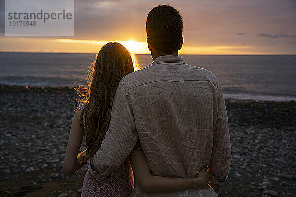 Young girlfriend and boyfriend at beach enjoying sunset