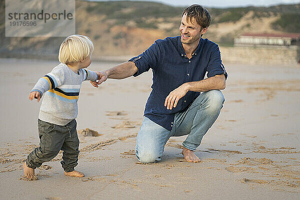 Glücklicher Mann hält Händchen mit Junge am Strand