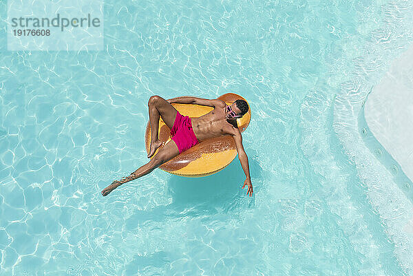 Man with inflatable float in swimming pool